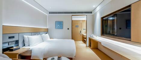 A hotel room with a bed, bedside table, chair, and a large window.