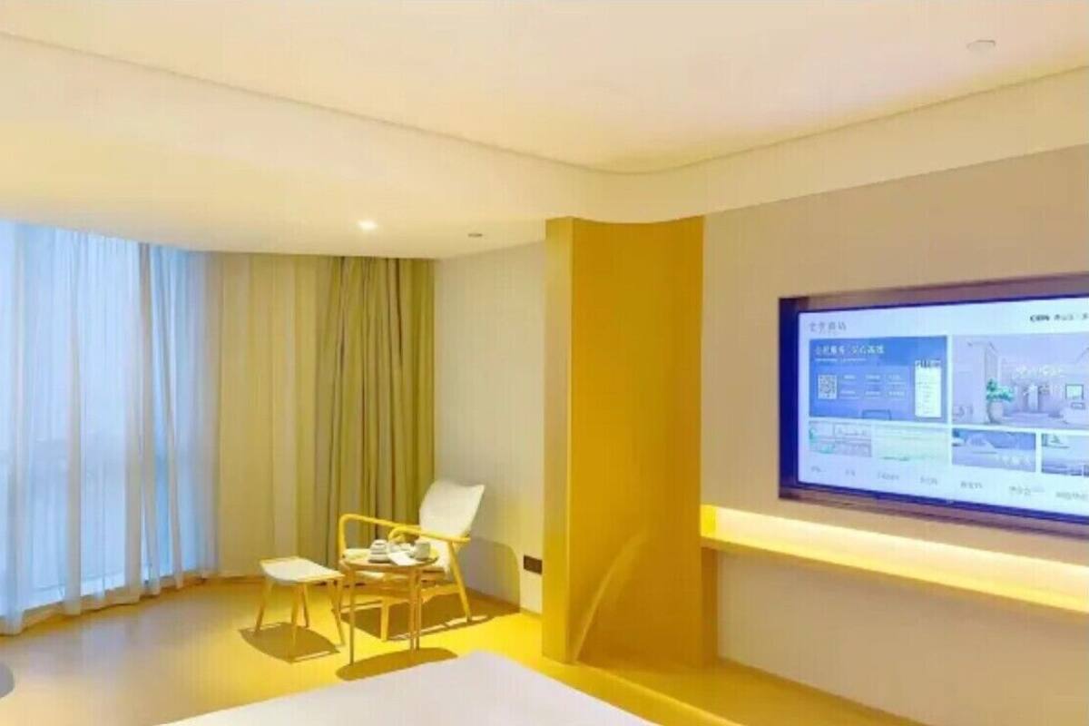 Une chambre d’hôtel équipée d’un lit, d’un bureau, d’une chaise, d’une télévision et d’une fenêtre avec des rideaux.