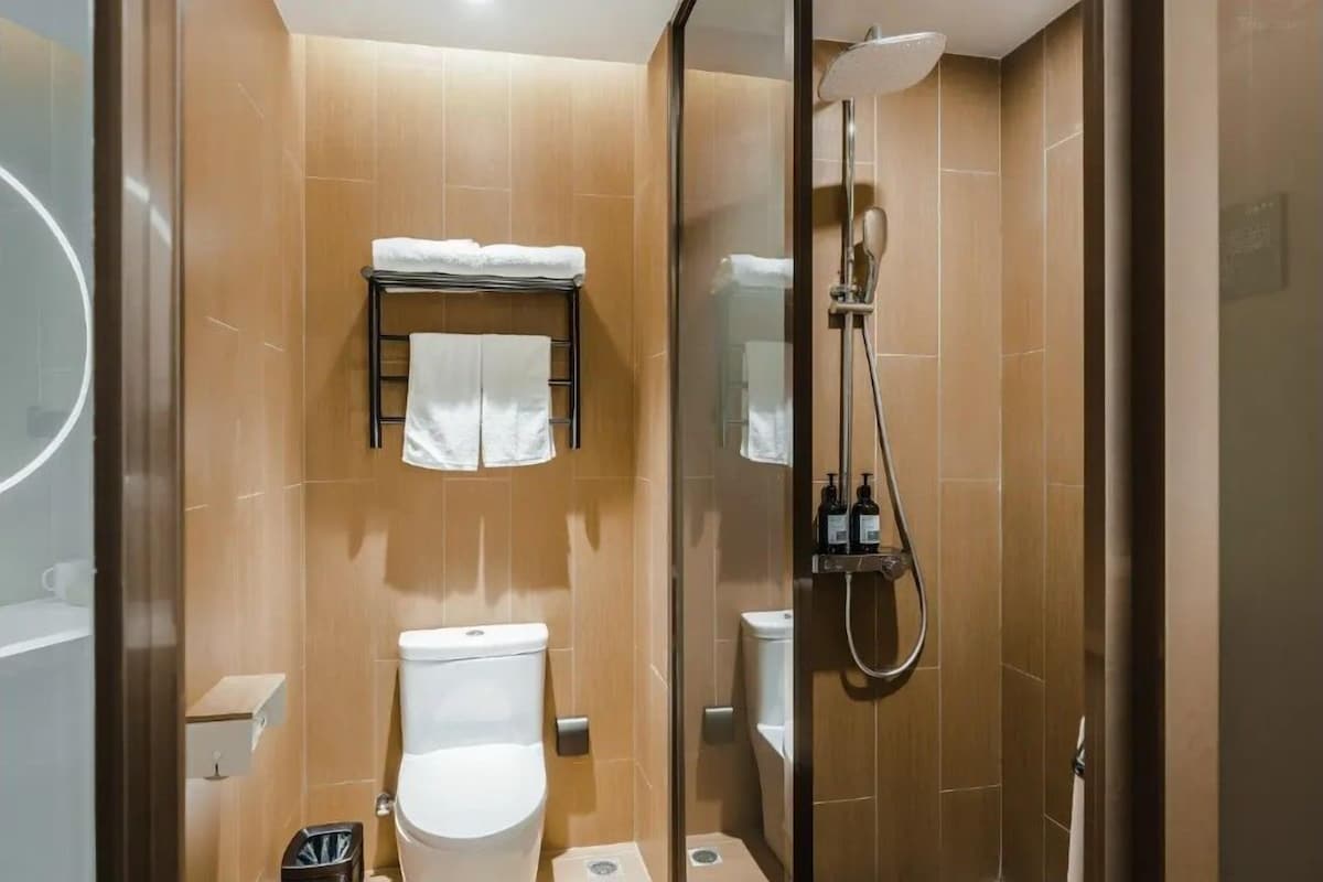 Moderni kylpyhuone, jossa on lasiseinällä varustettu suihku, wc ja pyyhekoukku.