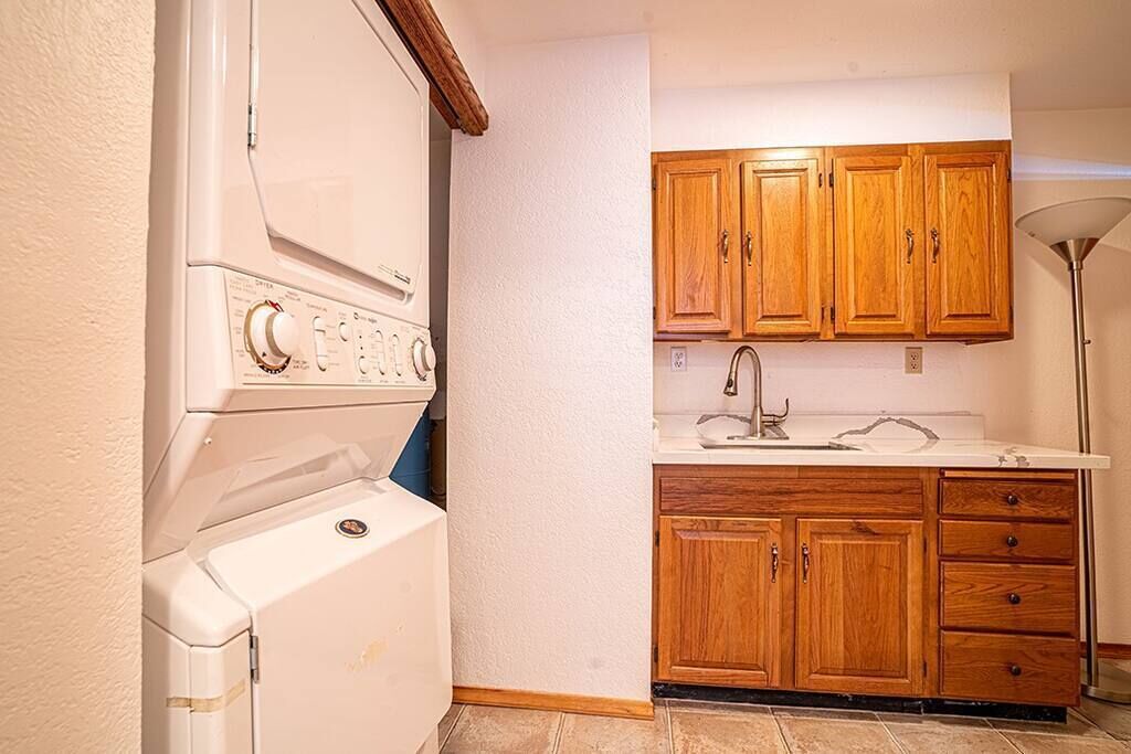 Une cuisine de taille réduite, dotée de meubles de rangement en bois, d’un four encastré et d’un évier.