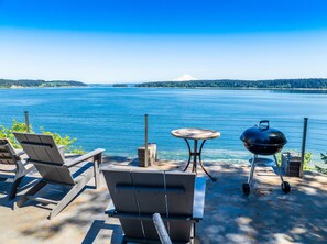 Een terras aan het meer met zitplaatsen buiten en een barbecue.