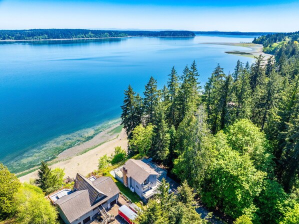 A lakeside property with a dock, a small docked boat, and a cabin with a large window overlooking the water.