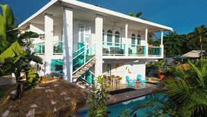A two-story white house with a glass staircase, a pool, and tropical plants. - 4 Bedrooms,5 beds, 3 Full bathrooms,Sleeps up to 8 with private pool (rincon)