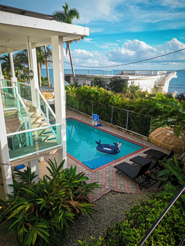 A swimming pool with a blue inflatable shark, surrounded by lounge chairs and a glass railing. - 4 Bedrooms,5 beds, 3 Full bathrooms,Sleeps up to 8 with private pool (rincon)