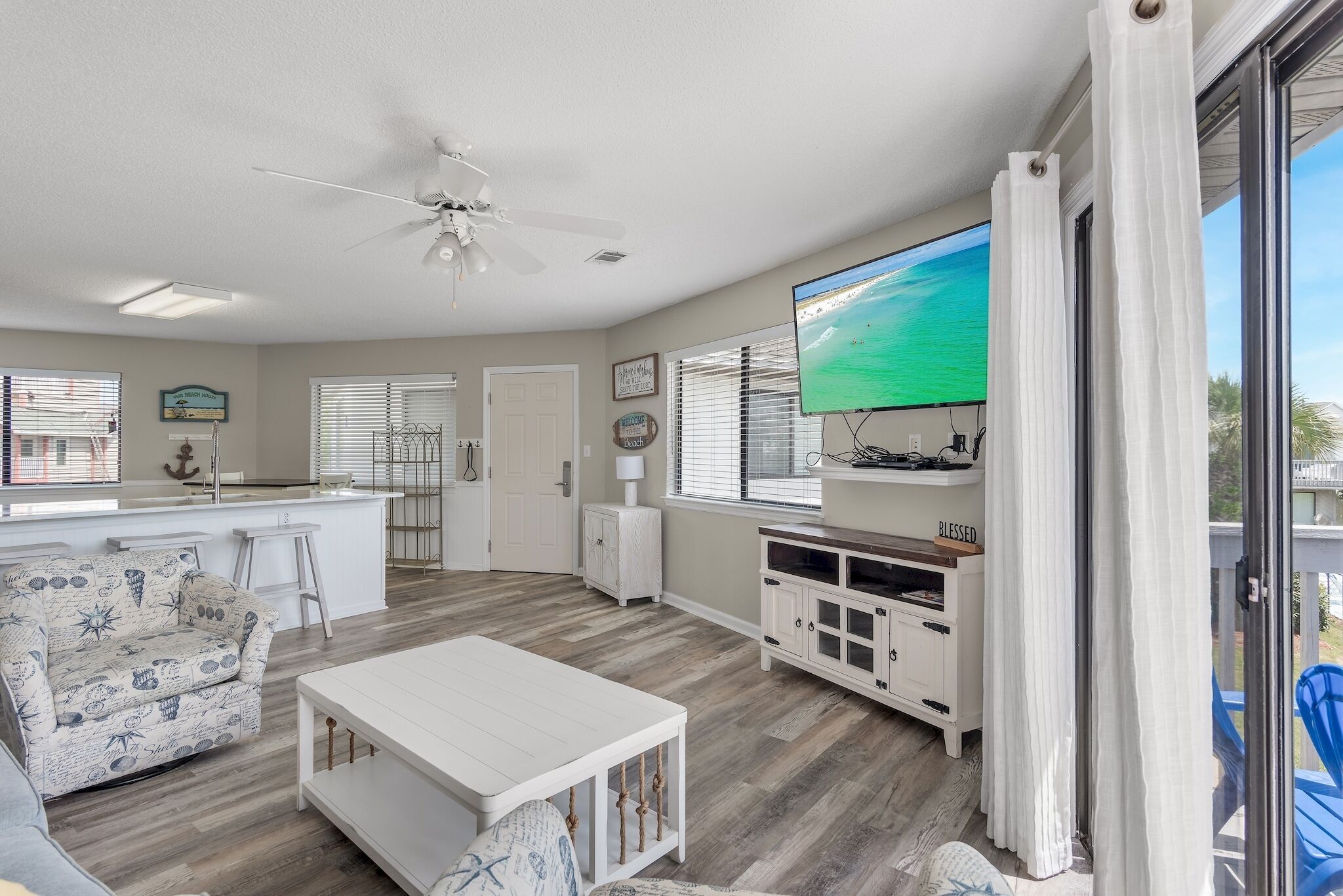 A spacious living area with a white sofa, a coffee table, and a TV mounted on the wall.