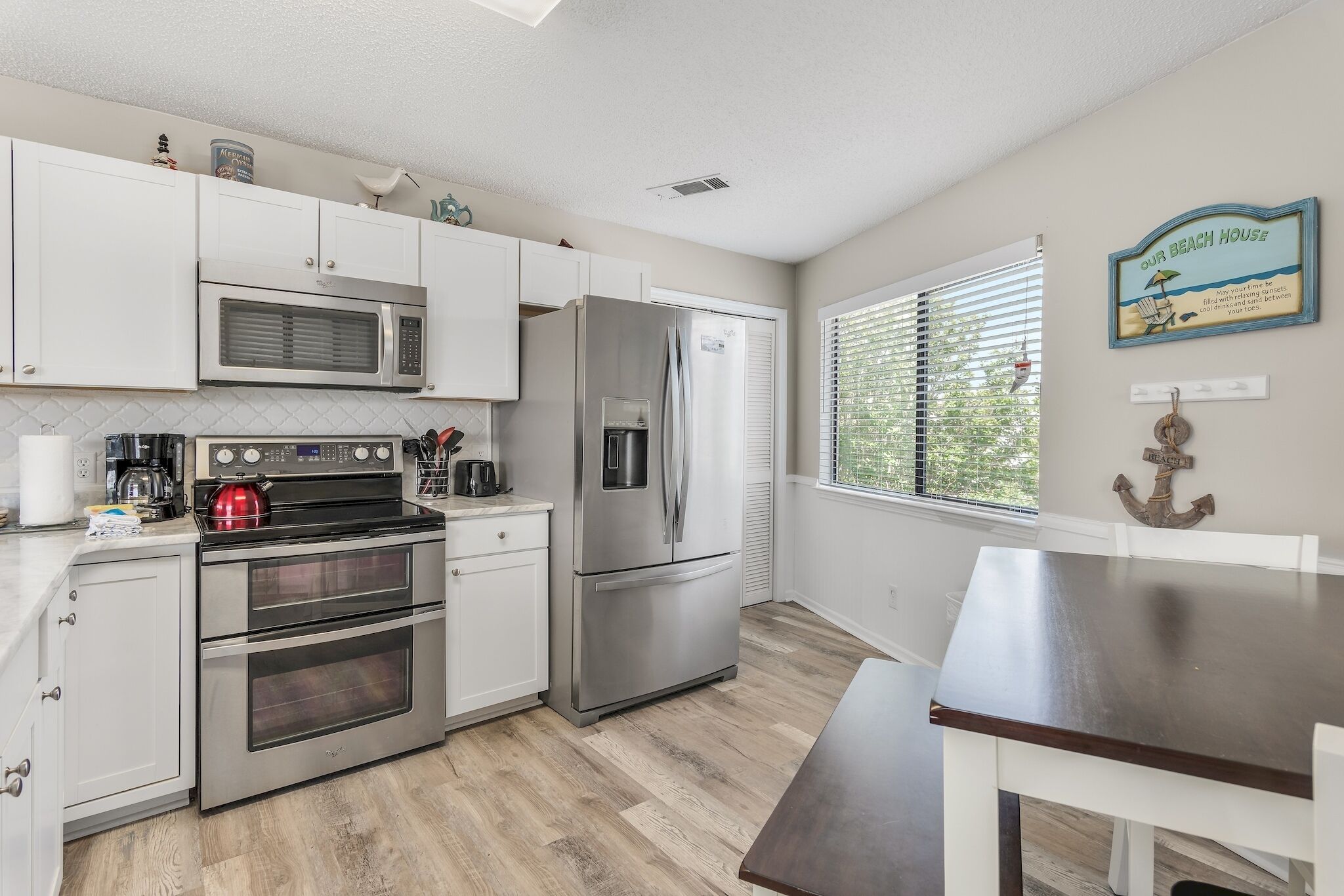 A kitchen with white cabinets, stainless steel appliances, and a wooden floor.