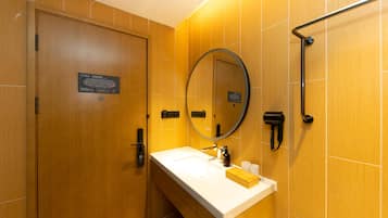 A modern bathroom with a wooden door, a white sink, a mirror, and a towel rack.