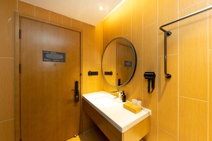 A modern bathroom with a wooden door, a white sink, a mirror, and a towel rack. - Ji Hotel (Wuhan)