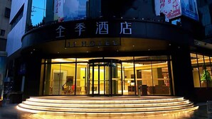 L’entrée d’un hôtel, avec une porte tournante et une enseigne indiquant « JI HOTEL ».
