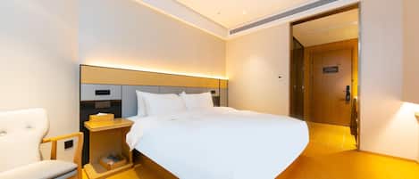 Une chambre d’hôtel moderne, dotée d’un grand lit, d’une table de chevet, d’une chaise et d’une porte donnant accès à la salle de bain.
