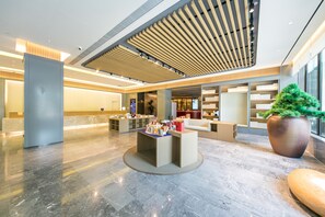 A modern lobby with a reception desk, seating area, and a large potted plant. - Ji Hotel (Wuhan)