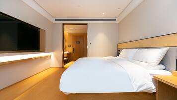 A modern hotel room with a large bed, bedside table, and a flat-screen TV mounted on the wall.