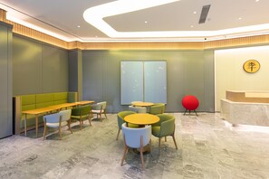 A modern interior with a reception desk, seating area with tables and chairs, and a large window. - Ji Hotel (Wuhan)