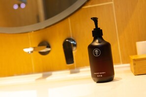 A hand wash bottle on a bathroom counter with a mirror and a wooden panel in the background. - Ji Hotel (Wuhan)