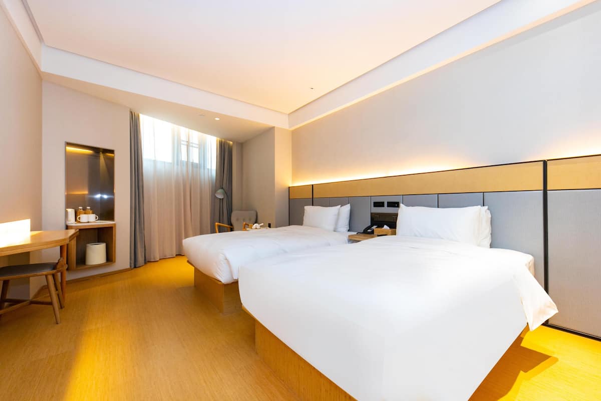 A hotel room with two beds, a desk, and a chair.