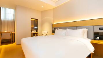Una habitación de hotel moderna con una cama grande, mesitas de noche, una silla y un espejo.