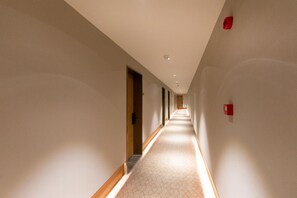 Un long couloir étroit, doté d’un tapis à motifs et de boiseries.