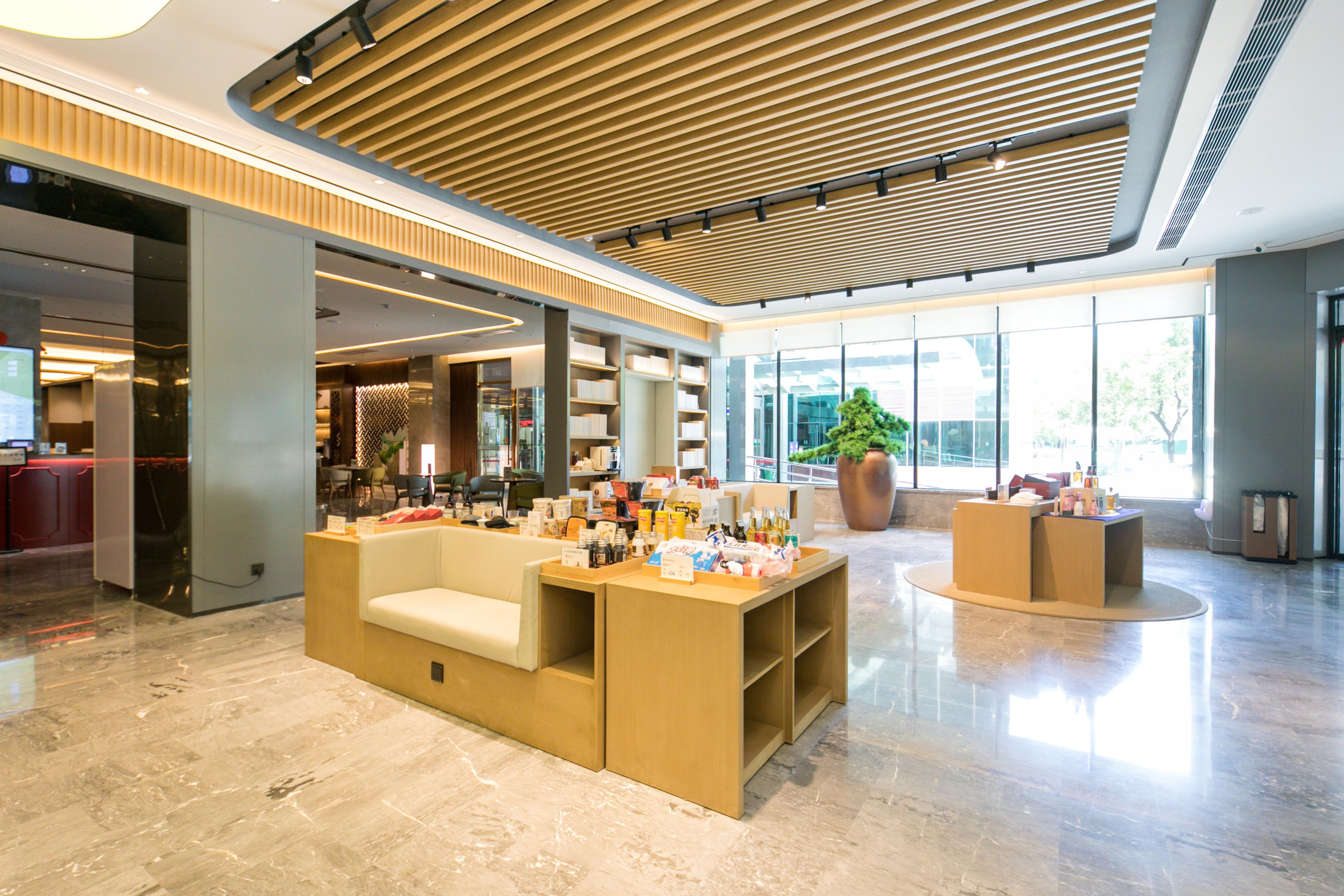 A spacious lobby with a reception desk, seating area, and large windows offering views of the outdoors.
