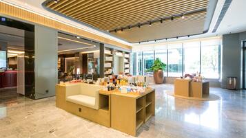 A spacious lobby with a reception desk, seating area, and large windows offering views of the outdoors.