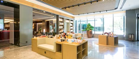 A spacious lobby with a reception desk, seating area, and large windows offering views of the outdoors.