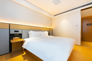 A modern hotel room with a large bed, a bedside table, and a built-in shelf. - Ji Hotel (Wuhan)
