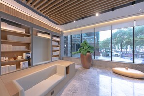 A modern lobby with a seating area, a large potted plant, and a view of the street through large windows. - Ji Hotel (Wuhan)