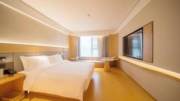 Een moderne hotelkamer met een groot bed, nachtkastje en een aan de muur bevestigde televisie.