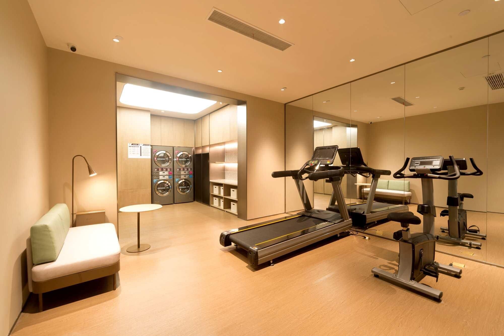 A gym with exercise equipment, a seating area, and a laundry room.