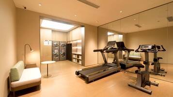 A gym with exercise equipment, a seating area, and a laundry room.