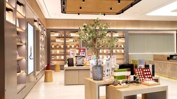A modern bookstore interior with wooden shelves, a central display table, and a potted plant.