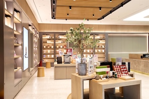 A modern bookstore interior with wooden shelves, a central display table, and a potted plant. - Ji Hotel Pangdonglai Life Plaza Old Pedestrian St (Xinxiang)