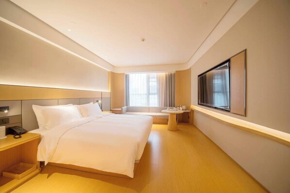 Una habitación de hotel moderna con una cama grande, una mesita de noche y un televisor montado en la pared.