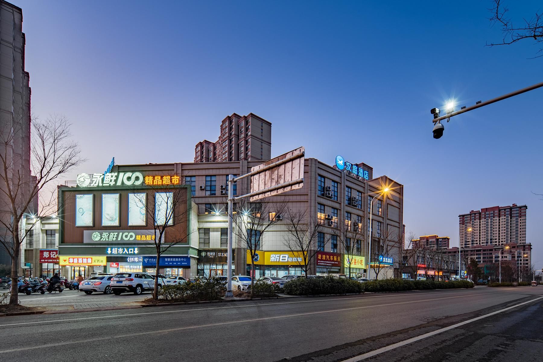 Un edificio comercial de varios pisos con diversas tiendas, incluyendo un letrero llamativo para '永鲜超市'.