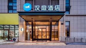 A hotel entrance with a modern design, featuring a prominent logo and signage above the doors.