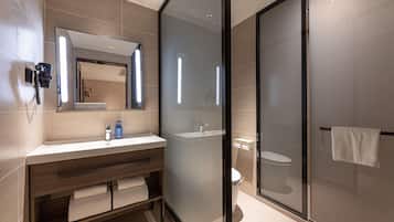 A modern bathroom with a glass shower enclosure, a wooden vanity, and a large mirror.