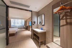 Un baño de hotel moderno con un espejo grande, un lavabo y una zona de ducha.