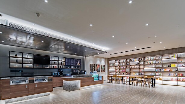A modern interior with a kitchen area, a dining space, and a bookshelf filled with books.