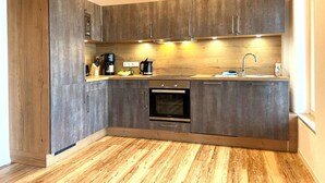A modern kitchen with dark wood cabinets, a built-in oven, and a wooden floor.