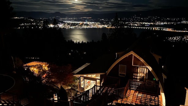 A house with a balcony and a view of a cityscape at night.