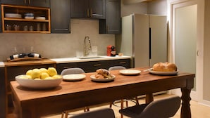 A modern kitchen with dark cabinets, a wooden dining table, and a refrigerator.