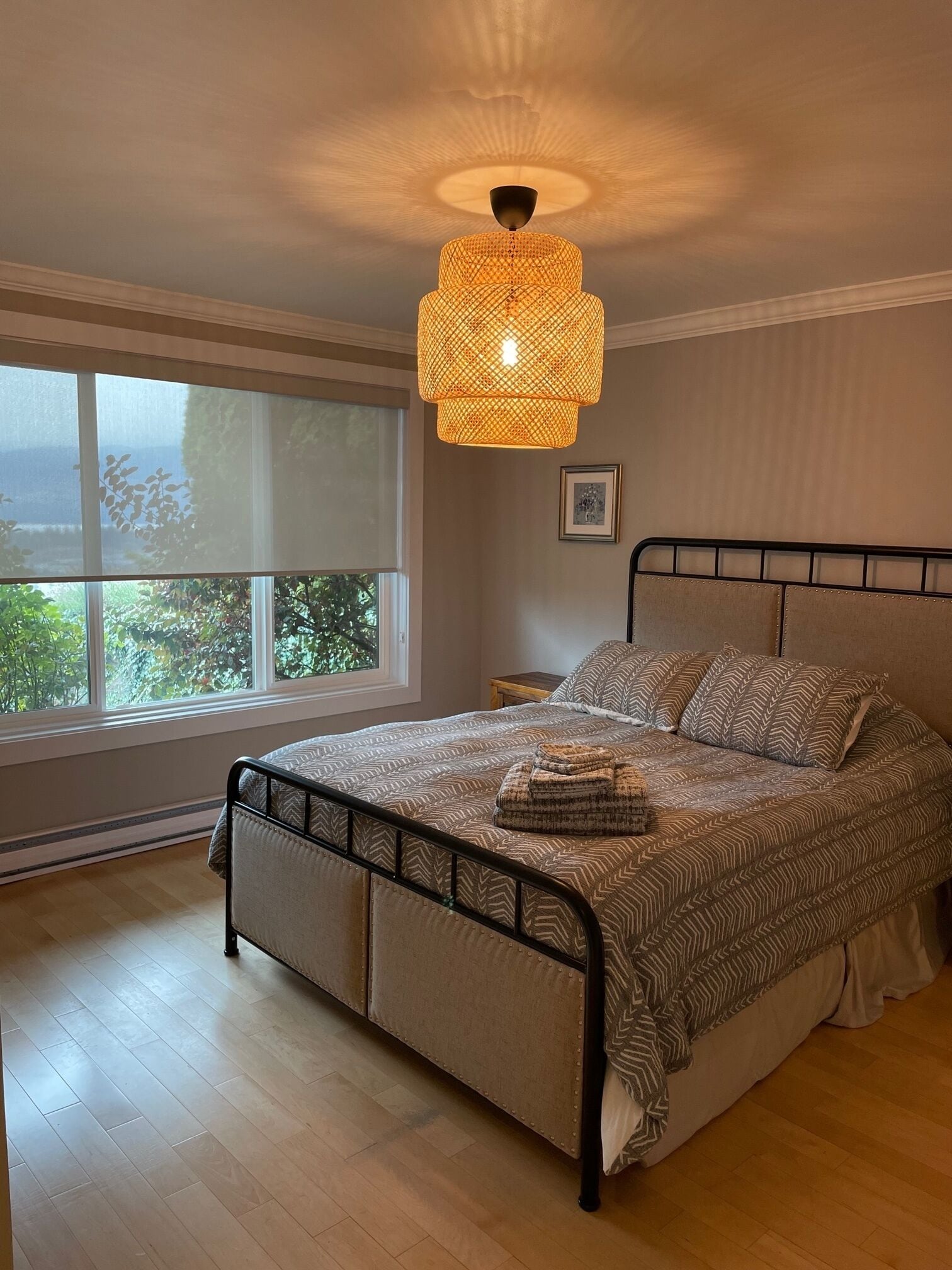 A bedroom with a bed, a window, and a hanging light fixture.