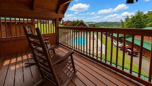 A wooden deck with a rocking chair, a pool, and a view of houses and greenery. - Groot's Place - 5min from parkway - massage chair/pool table/foosball (Pigeon Forge)