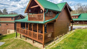 A log cabin with a balcony and a green roof. - Groot's Place - 5min from parkway - massage chair/pool table/foosball (Pigeon Forge)