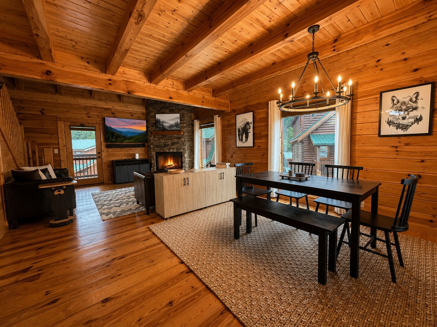 L’intérieur d’une cabane en rondins, avec une cheminée en pierre, une table à manger en bois et une vue sur l’extérieur par une fenêtre.