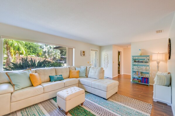 A living room with a sectional sofa, ottoman, and a bookshelf.