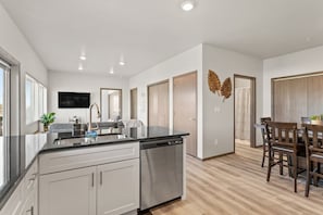 Enjoy meals in this stylish kitchen and dining area with a central island, dishwasher, and wooden table.