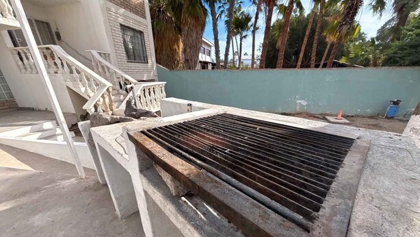 A concrete structure with a metal grill, a staircase, and a building in the background. - Shoreline Condo 4 Desert Oasis Free Wifi Cool  AC (San Felipe)