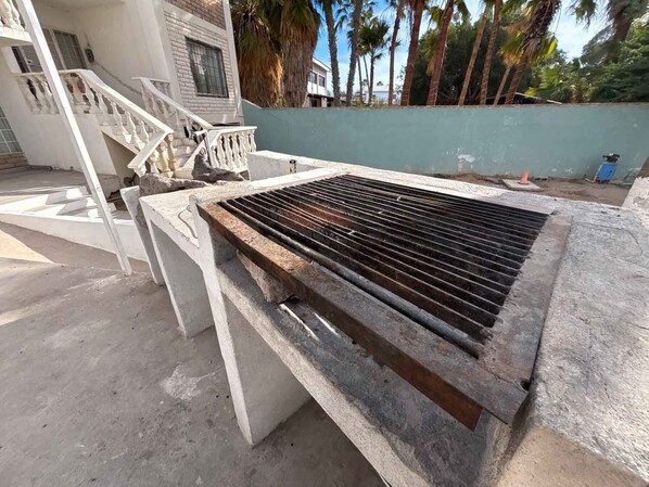 A concrete structure with a metal grill, a staircase, and a building in the background.