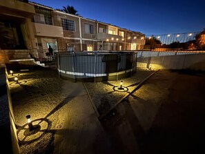A building with a swimming pool, outdoor lighting, and a staircase leading to the entrance.