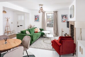A modern living room with a green sofa, red armchair, and a round coffee table. - ✨ Stylish Grade II Listed Cottage in the Heart of Alnwick (Northumberland)